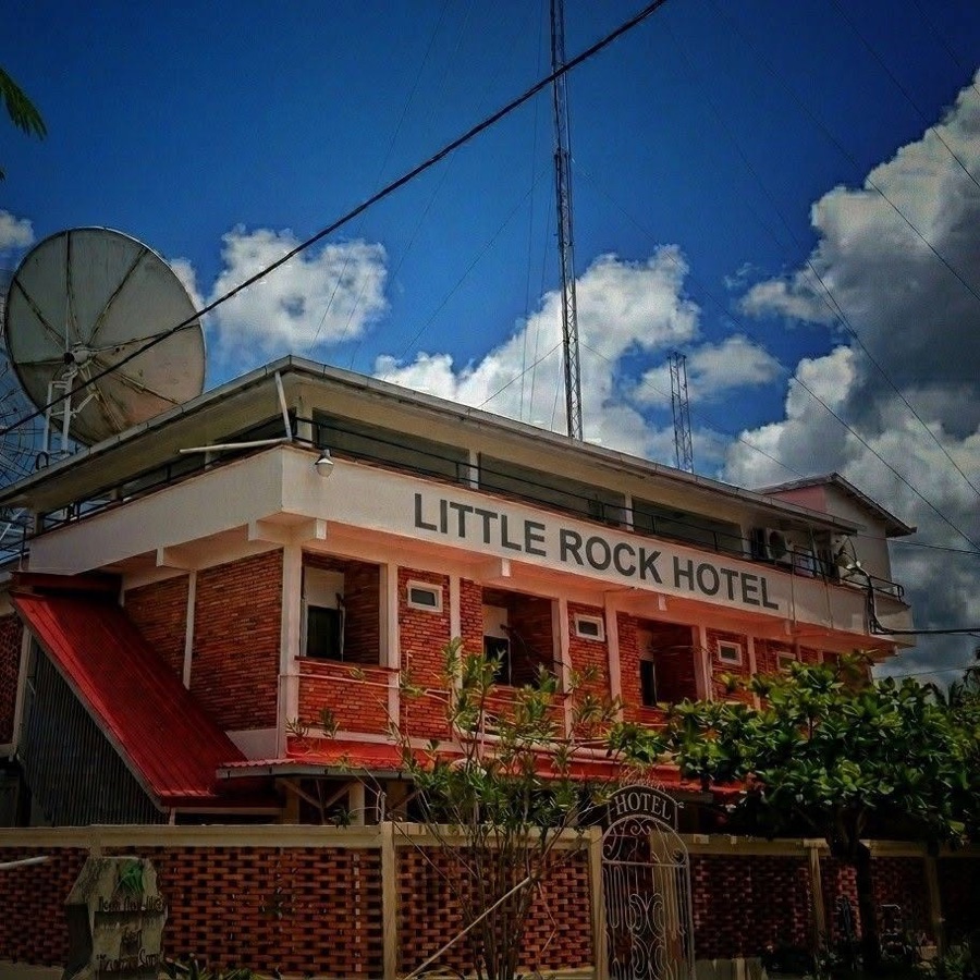 The Little Rock Hotel โ red brick and white trim, with the broadcast tower and satellite dish rising behind it